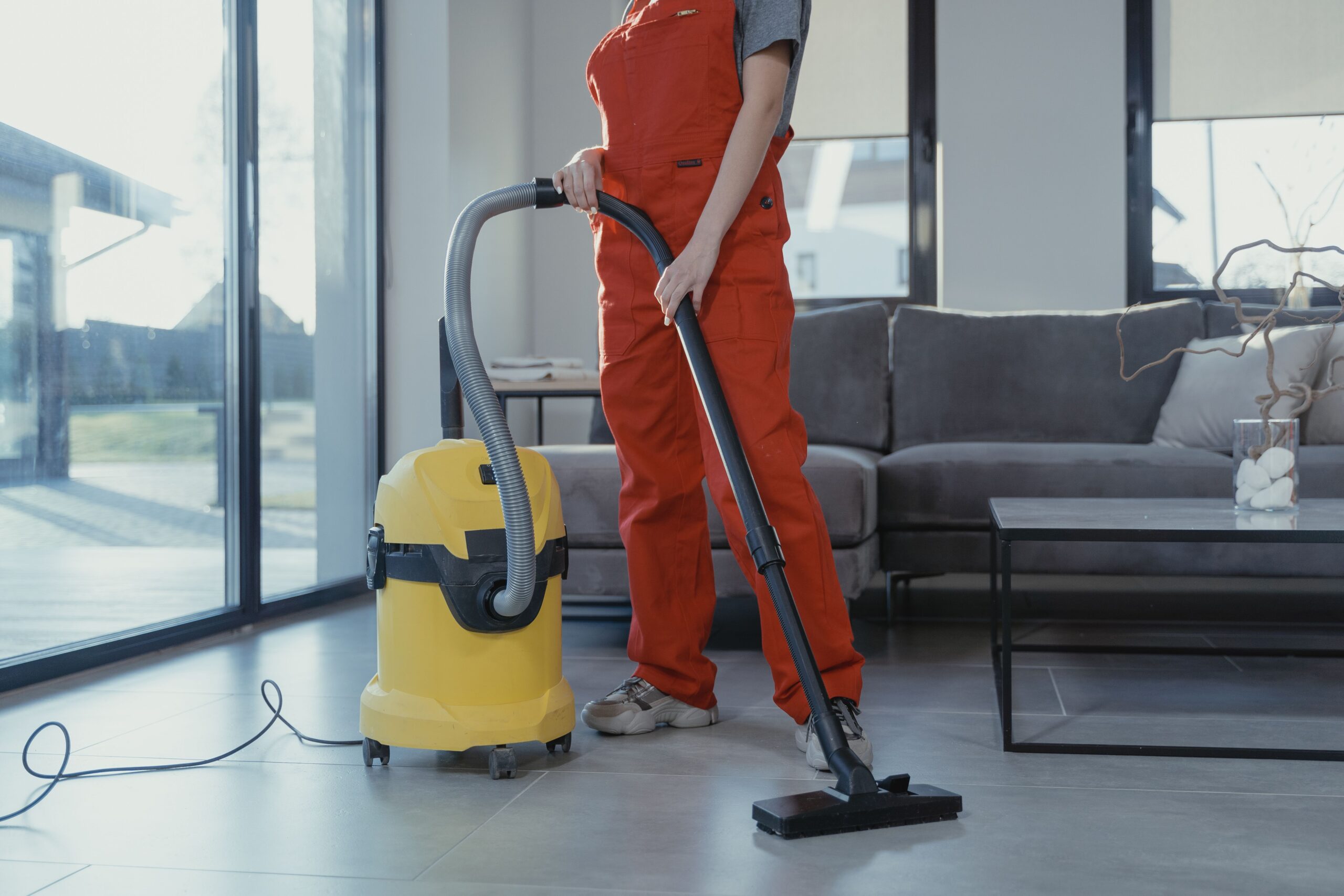 Professional cleaner vacuuming a bright living room